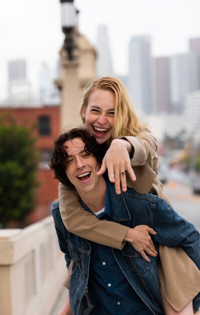 Happy couple posing outdoors in the city with engagement ring