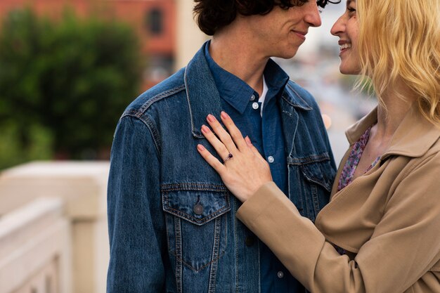 Happy couple posing outdoors in the city with engagement ring