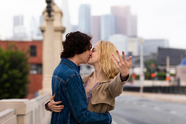 Happy couple posing outdoors in the city with engagement ring