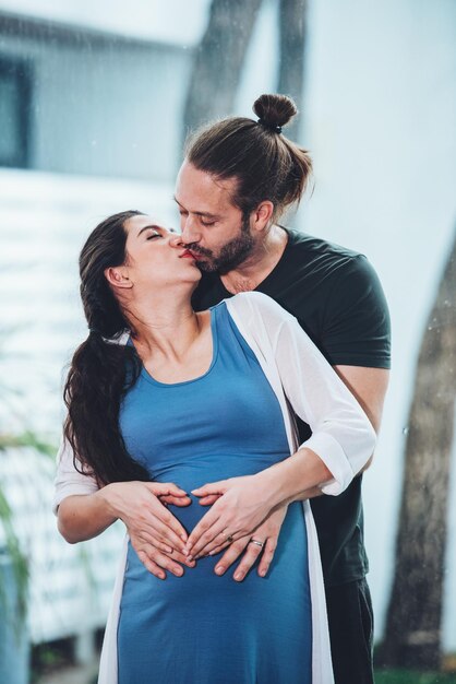 Happy couple pregnant woman and husband stay home in living room Happy couple taking care together