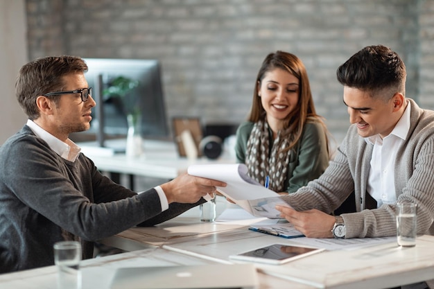 Happy couple signing a contract on a meeting with their real estate agent in the office