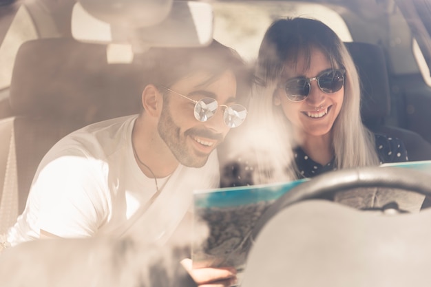 Free photo happy couple sitting in car looking at map