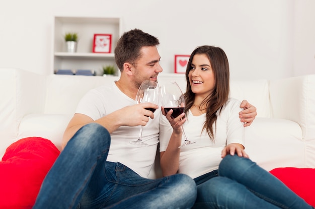 Happy couple spending romantic time with red wine at home