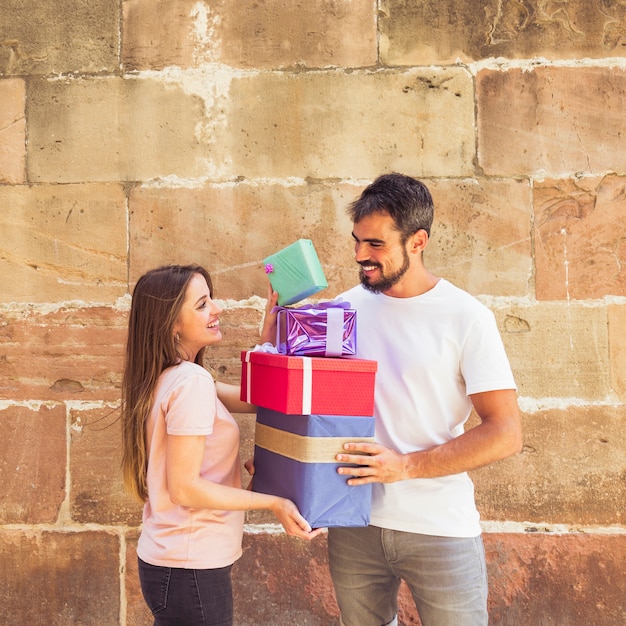 Happy couple stacking gifts against grunge wall