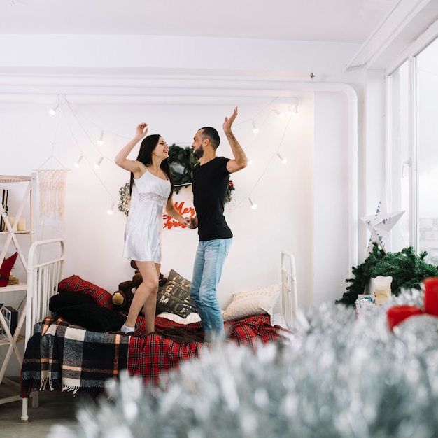 Happy couple standing on bed 