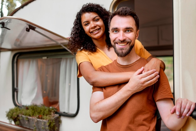 Happy couple standing in front of camper van