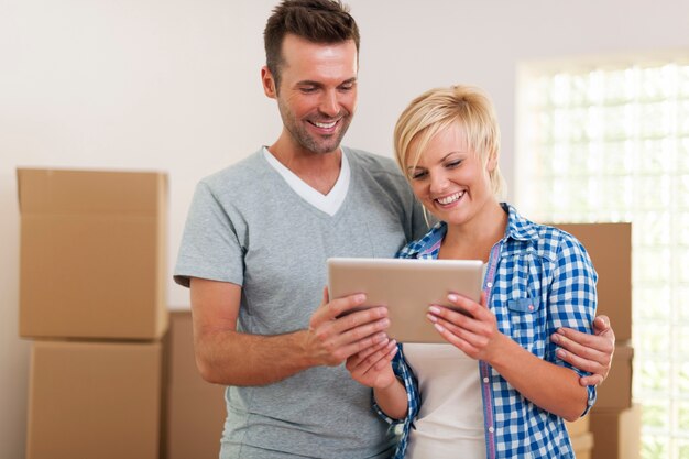 Happy couple using digital tablet during the moving home