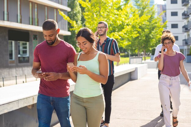 Happy couple using mobile phones outdoors