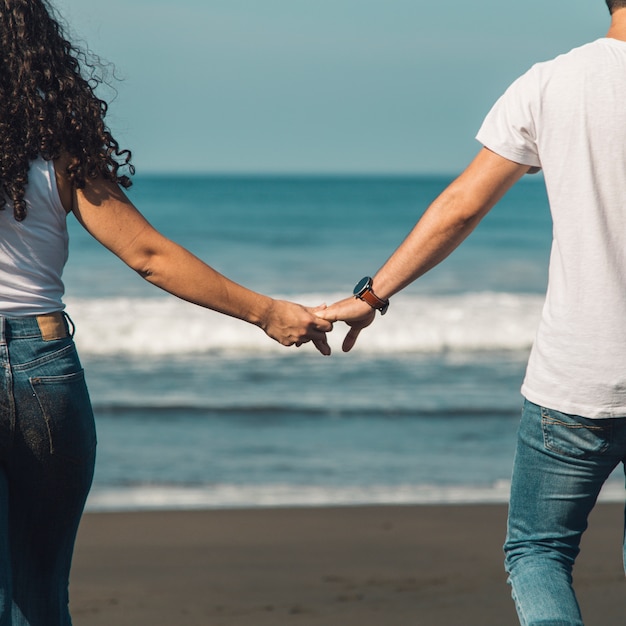 Happy couple walking on beach and looking on ocean surf waves