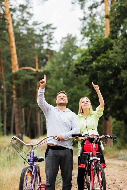 Happy couple with bicycles pointing up