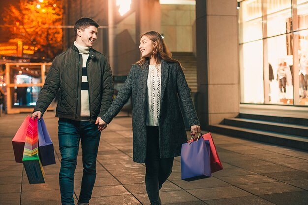 The happy couple with shopping bags enjoying night at city