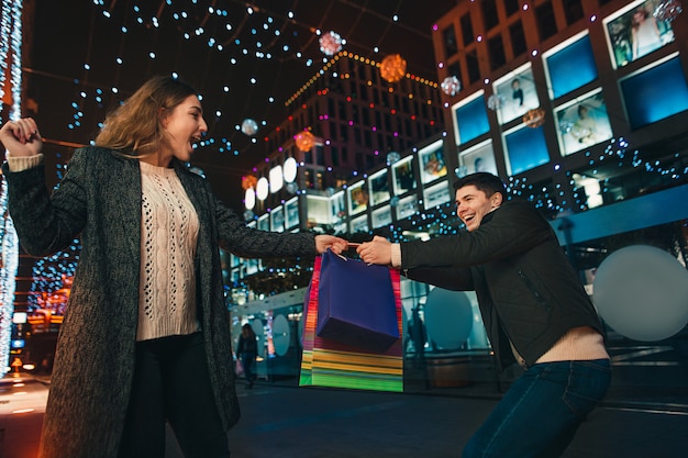 Free Photo the happy couple with shopping bags enjoying night at city