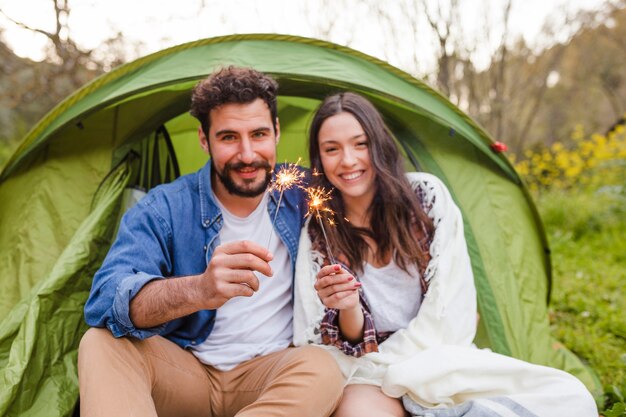 Happy couple with sparklers near tent