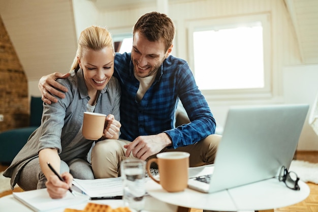 Free Photo happy couple writing notes while going through home finances during their coffee time