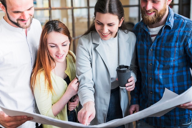 Free photo happy coworkers working on blue print in office