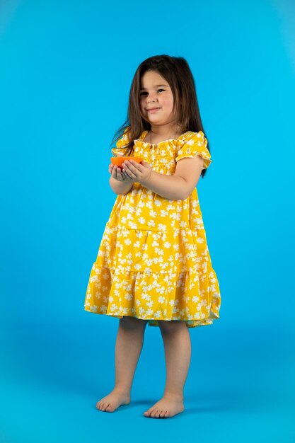 Happy cute baby girl fashionable yellow baby clothes posing studio on blue background