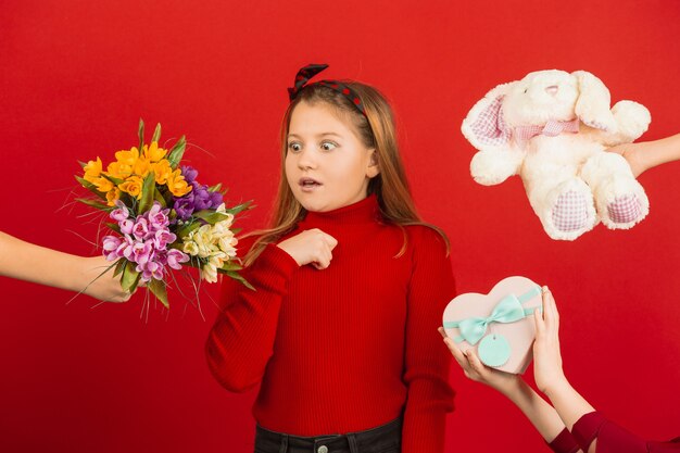 Happy, cute caucasian girl isolated on red studio