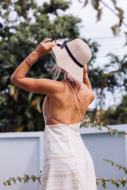 Free Photo happy cute romantic caucasian woman in summer elegant white open back dress, straw hat