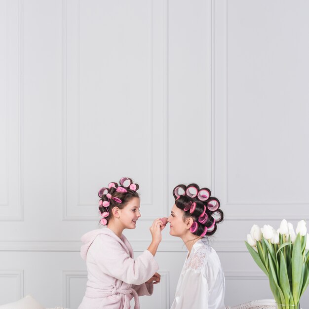 Happy daughter putting powder on mothers face