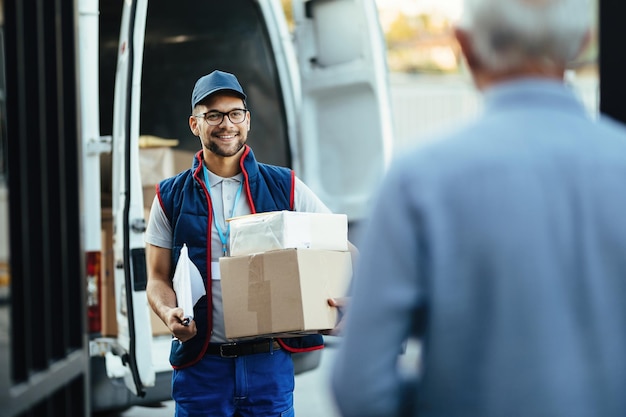 Free photo happy deliverer carrying packages while making home delivery to his customer