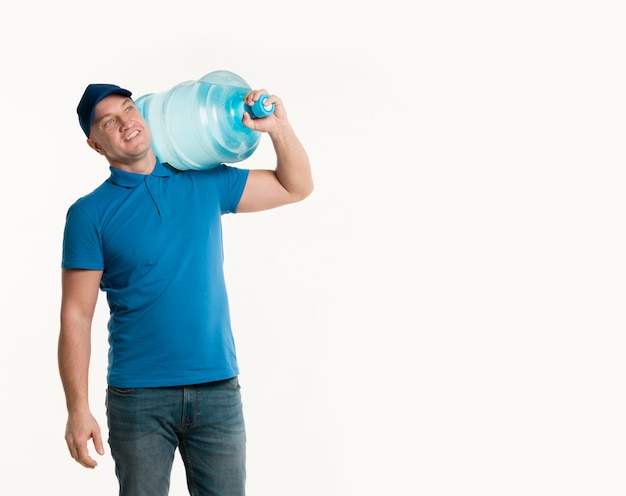 Free photo happy delivery man holding water bottle on shoulder with copy space