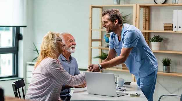 Free photo happy doctor greeting senior couple and shaking hands with a woman at his office