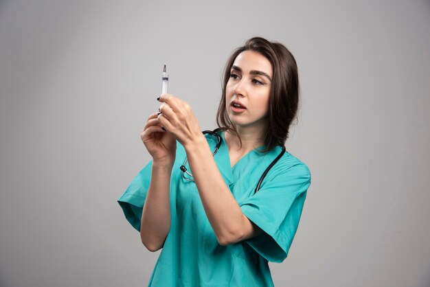 Happy doctor in uniform posing with syringe. High quality photo