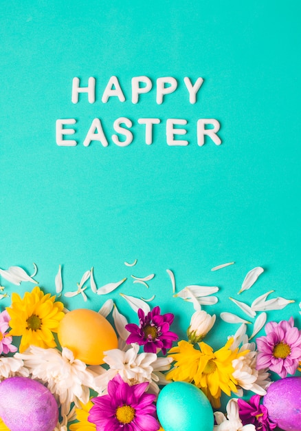 Happy Easter words near bright eggs and flower buds