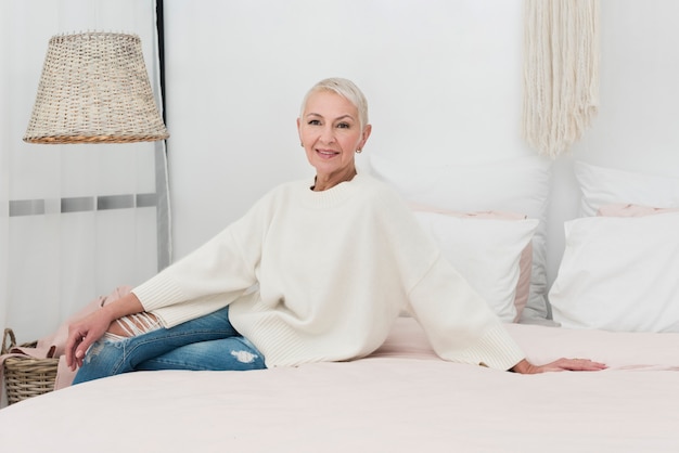 Happy elderly woman posing in bed