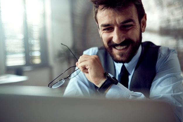 Happy entrepreneur reading an email on laptop in the office