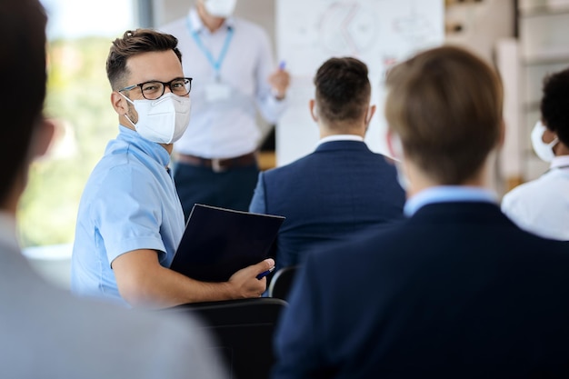 Happy entrepreneur with face mask attending business seminar in board room