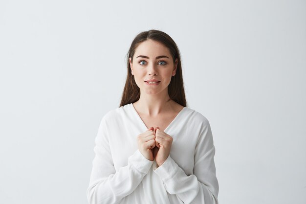 Happy excited young business woman biting lips holding jaws .