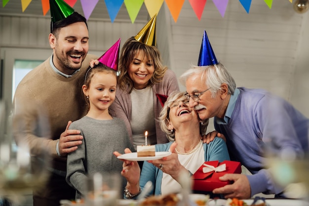 Free photo happy extended family celebrating senior woman's birthday and surprising her with a cake