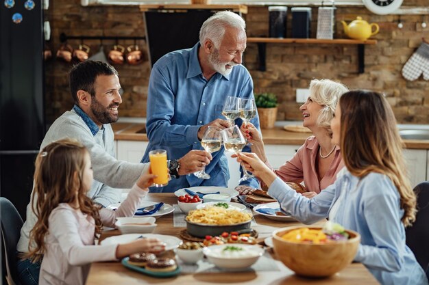 Happy extended family enjoying in a lunch and toasting at dining table Focus is on senior couple