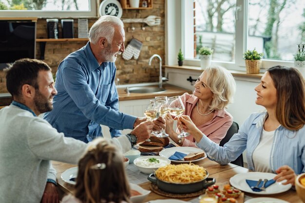 Happy extended family enjoying in a lunch and toasting with wine at dining table