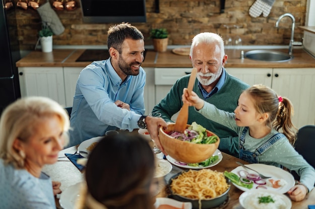 Happy extended family having lunch and eating healthy food at dining table