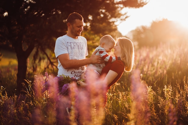 Happy family couple with little son pose on the field of lavander 