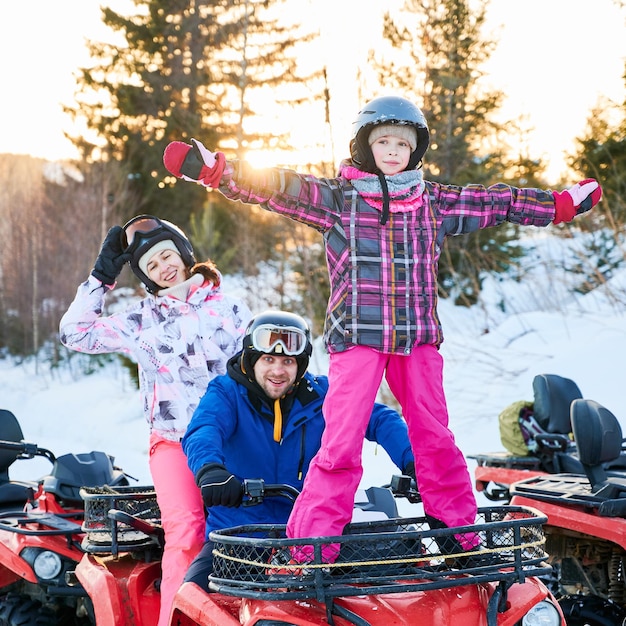 Free photo happy family driving quad bike in winter mountains