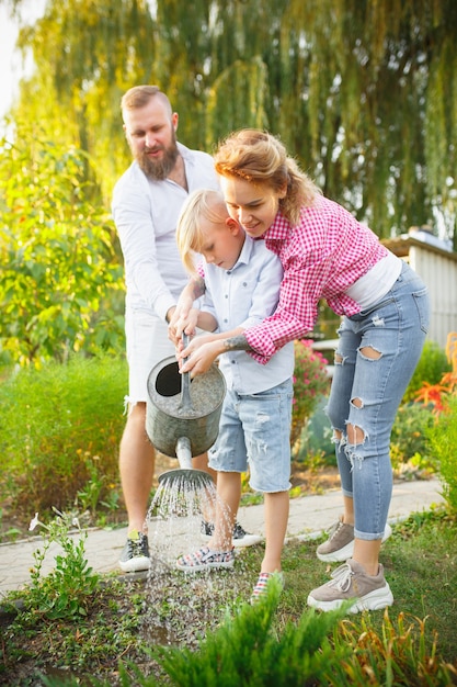 Free photo happy family during watering plants in a garden outdoors