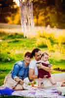 Free photo happy family lies on white blanket on the green lawn