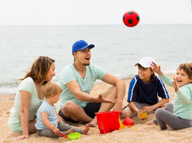 Free photo happy family playing with ball at sandy beach