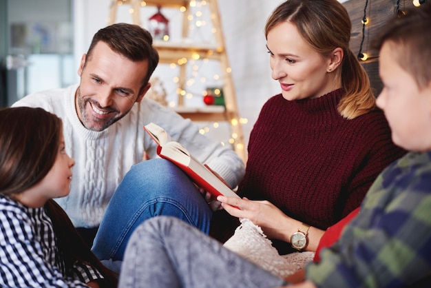 Free photo happy family reading a book in christmas time