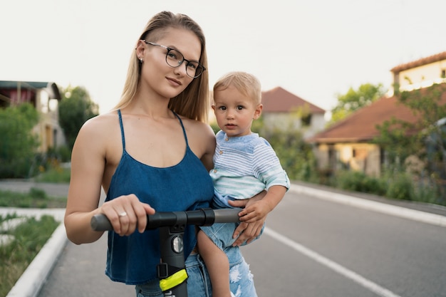 Happy family riding scooter in the neighborhood on the road.