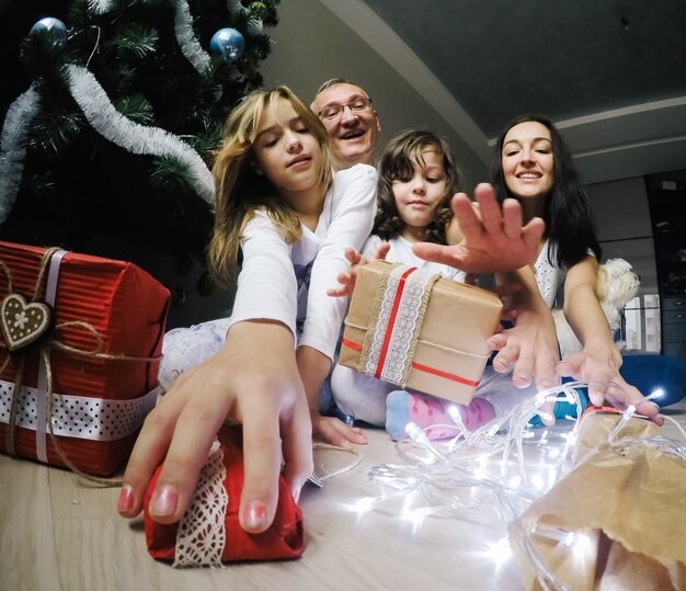 Happy family, sit on a floor near a fir-tree