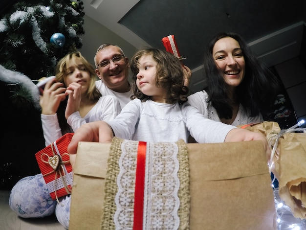 Free Photo happy family, sit on a floor near a fir-tree