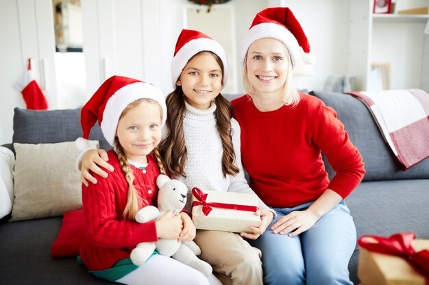 Happy family sitting on the sofa and unwrapping Christmas presents