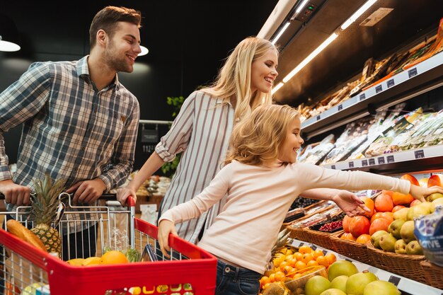 Happy family with child and shopping cart buying food