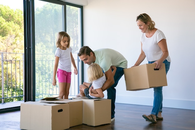 Happy family with kids near carton boxes standing in living room