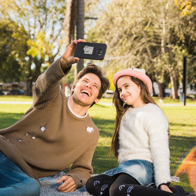 Happy father and daughter taking selfie with mobile phone