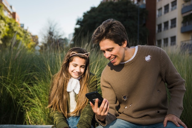 Happy father showing something to his daughter on mobile phone